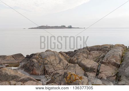 Gray rocks and the sea and a island in the background. No people