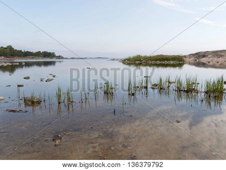 Small harbor reed straw and the sea the sky reflecting in the water surface. No people