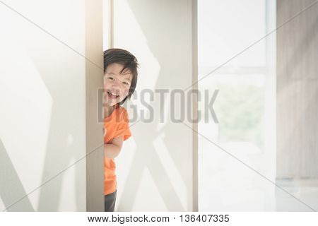 Cute asian child hiding behide the wall