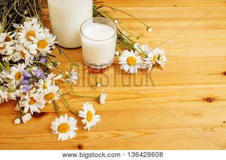 Simply stylish wooden kitchen with bottle of milk and glass on table, summer flowers camomile, healthy foog moring concept noone
