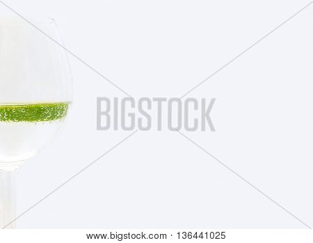 Slice of lime in a glass of drink on white background on left hand side