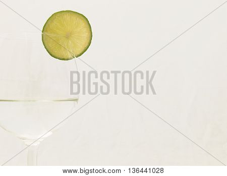 Slice of lime on a glass of drink on white background on left hand side
