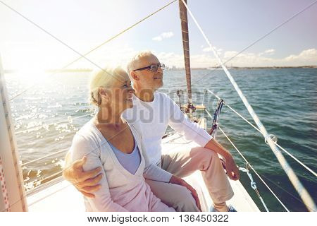 sailing, age, tourism, travel and people concept - happy senior couple hugging on sail boat or yacht deck floating in sea
