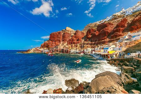 The waves beat against the rocks on a sunny summer day at Old port Ammoudi of Oia village at Santorini island in Aegean sea, Greece