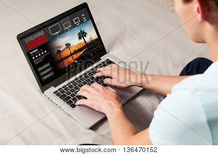 Man watching series and movies in a computer. View of laptop screen from his shoulder.