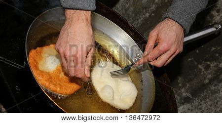 Two Large Pancakes Dipped In Hot Oil In An Aluminum Pot