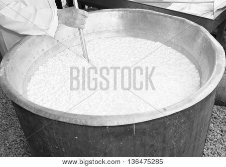 Cheesemaker Stirs The Curds Into The Big Copper Cauldron To Make