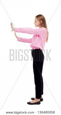 back view of business woman pushes wall.  Blond girl in a green skirt pushing something heavy right. The girl office worker in black trousers, put her hands in front of him.