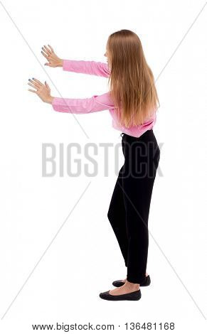 back view of business woman pushes wall.   Blond girl in a green skirt pushing something heavy right. girl office worker in black trousers shoves something in front of him.