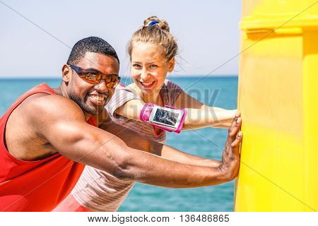 Multiracial friends making stretching after jogging next sea - Young people smiling and relaxing before a training session - Healthy lifestyle and sport concept - Soft warm saturated filter