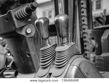 Old and dirty forklift operating levers control selective focus (black and white effect)