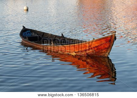 Wooden rowboat in warm evening light partly filled with water to get it waterproof