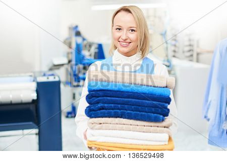 Girl worker holding a Laundry service clean towels and smiling
