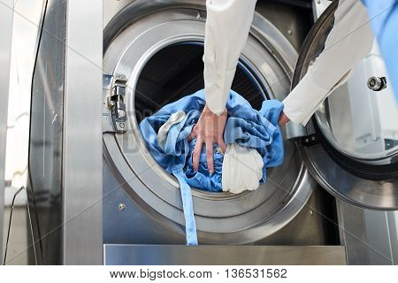 Hands to load the Laundry in the washing machine at the dry cleaners