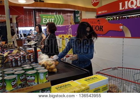 NAPERVILLE, ILLINOIS / UNITED STATES - NOVEMBER 3, 2015: Shoppers place their purchases on the conveyor belt at the check out line in the Super H Mart Korean supermarket in Naperville.