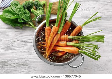 Carrots in colander on wooden table