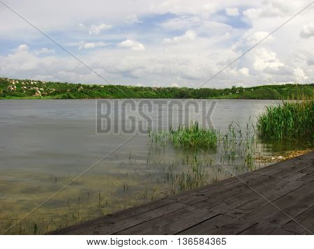 Lake with transparent water and pier for fishermen