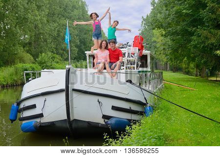 Family vacation, travel on barge boat in canal, happy parents with kids having fun on river cruise in houseboat