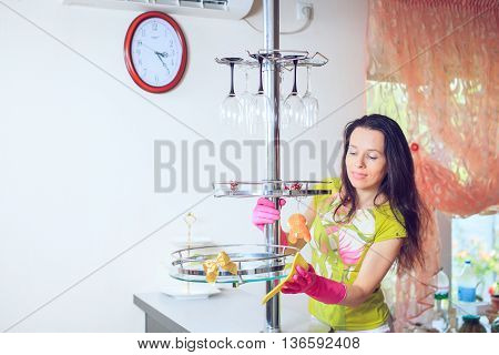 Beautiful cheerful brunette woman in gloves cleaning modern kitchen