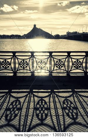The building of the National Library in Riga at sunset with long shadows from the fence embankment on the pavement