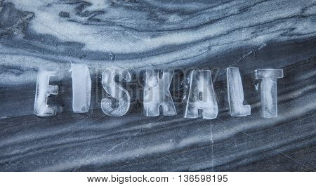 Eiskalt caption made of ice cubes on dark marble meaning ice cold in German