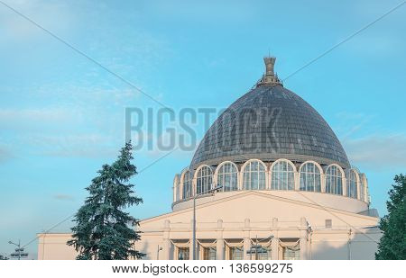 A modern building with a large glass dome on a blue sky background