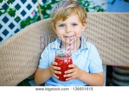 Adorable little kid boy drinking healthy fruits and vegetables juice smoothie in summer. Happy child enjoying organic drnk.