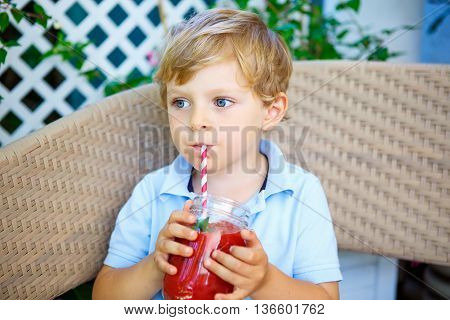 Adorable little kid boy drinking healthy fruits and vegetables juice smoothie in summer. Happy child enjoying organic drnk.