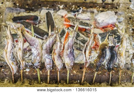 Fish with salt being grilled outdoors in Japan