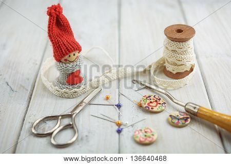 sewing tools like seam ripper, bobbin lace, pins, scissors, etcetera on wooden background