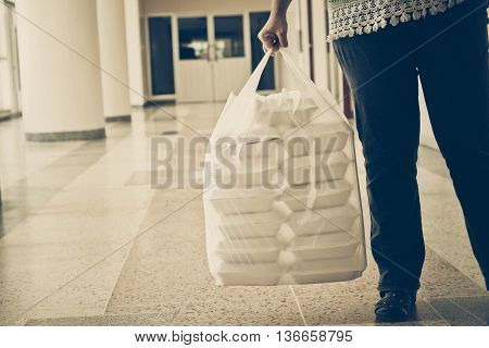 Hand holding foam boxes in plastic bag