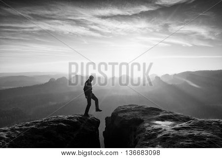 Hiker In Black Is Jumping Between Mountains Peaks.