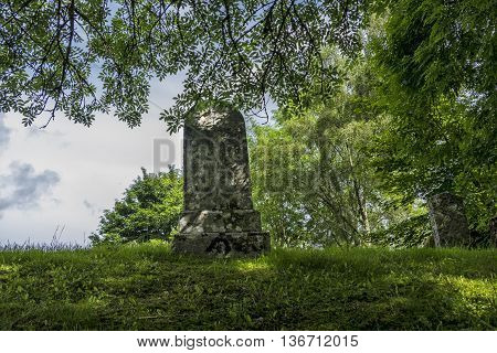 Ancient grave stone in Scottish graveyard surrounded by trees.