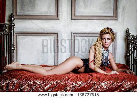 Blonge Woman in medieval corset  historic dress and lingerie  posing in bed