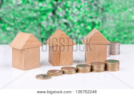 Wooden block houses and coin stacks in a row with a green background