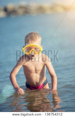 Little boy with snorkel by the sea. Cute little kid wearing mask and flippers for diving at sand tropical beach. Ocean coast.