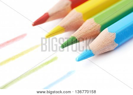 Four colorful drawing pencils composition with the traces of paint, isolated over the white background, close-up crop fragment