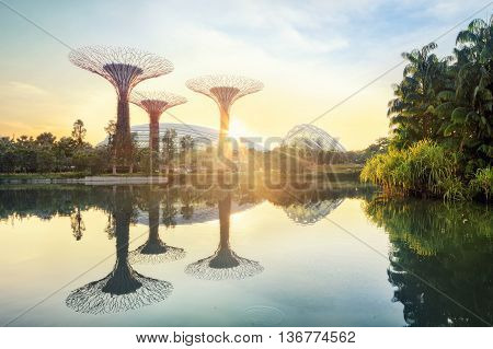 Singapore, Republic of Singapore - May 5, 2016: Supertree grove and Cloud garden greenhouse reflecting in pond at sunrise