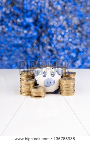 Piggy bank with a stack of coins and a blue blurry background