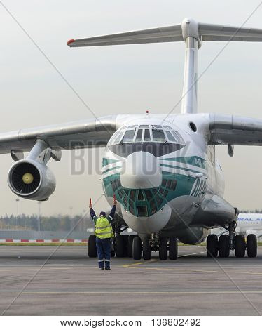 MOSCOW, RUSSIA - SEPTEMBER 26, 2014: Cargo airplane IL-76TD Alrosa airlines taxiing to the parking lot with the help of airport Marshal,