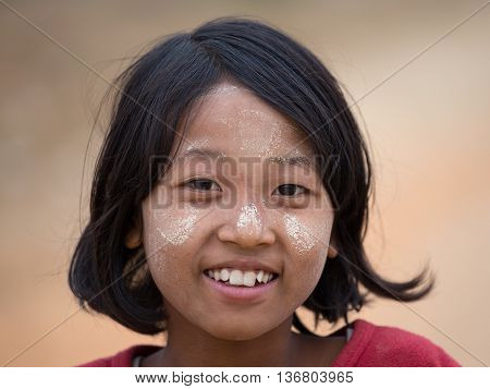 MRAUK-U MYANMAR - JANUARY 28 2016 : Unidentified young Myanmar girl with thanaka on her smile face is happiness. Thanaka is a yellowish-white cosmetic paste made from ground bark.