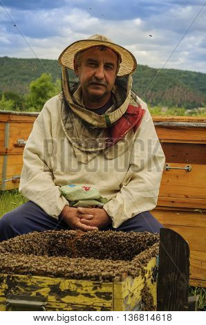 Beekeeper with the honey frame on the apiary