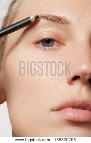 Beautiful Woman Drawing A Shape Of Eyebrows Using Cosmetic Brush. Make-up Artist Applying Make-up To