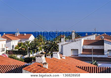 Roofs from terracotta tiles palm trees blue sea. Travel destination. Costa Dorada Spain. Horizontal.