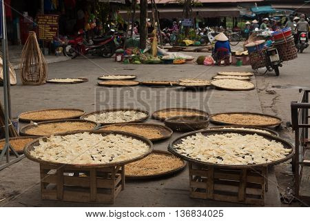 Market pavement vendor selling dried food in a street stall in Hoi An. The display includes, pulses, beans and chickpeas as well as banana leaf packages of food.