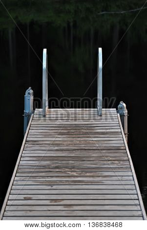 Small bridge for bathing in a forest lake a cool summer evening.