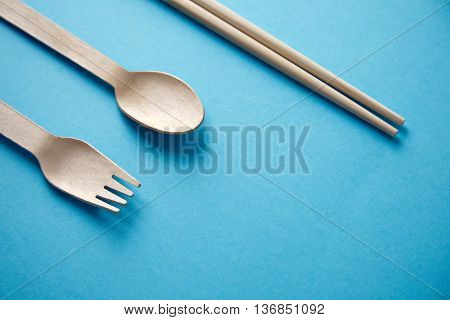 Various kitchen utencils for takeaway: asian chopsticks, spoon or fork made from recycled paper or wood, eco friendly, top view isolated on blue mockup