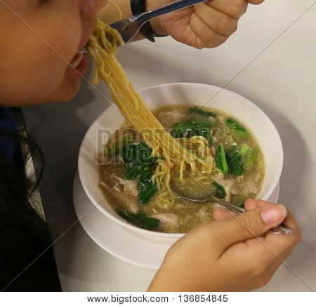 girl eating southern Thai pork and noodles, Hat Yai, Thailand