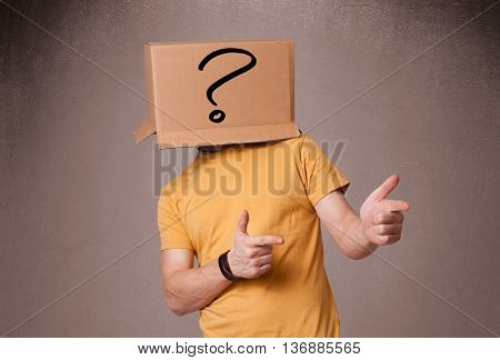 Young man standing and gesturing with a cardboard box on his head with question mark