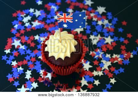 Happy Australia Day party food with red white and blue cupcake and Australian flag. Anzac Day. Celebration patriotism and holidays concept - close up of glazed muffin decorated with australian flag